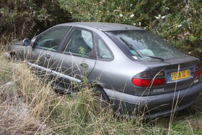 a car that is sitting in the grass by the trees