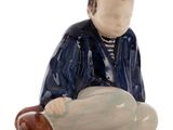 a figurine of a man sitting on the ground