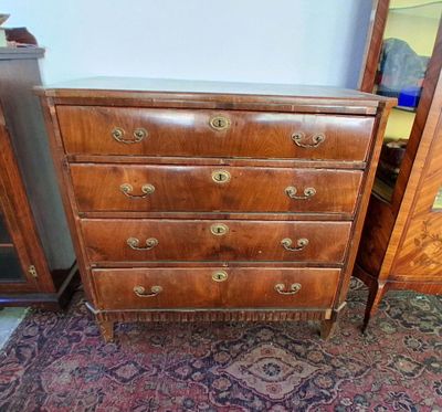 une commode ancienne dans une pièce où se trouve un tapis au sol