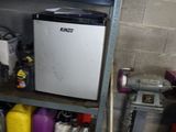 un petit réfrigérateur posé sur une étagère dans un garage