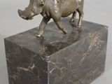 a bronze statue of a rhino on a marble block