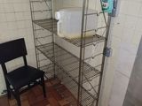 a metal shelf with a sink and a chair in a kitchen