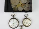 three silver pocket watches and a box of coins on a white surface