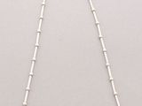 a white necklace with a long chain that has beads on it