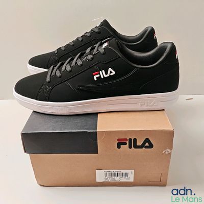 des chaussures de tennis Fila noires et blanches posées sur une boîte