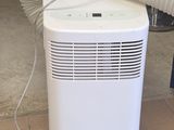un climatiseur blanc posé par terre près d'une fenêtre