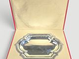 an open box with a silver tray inside of it on a white surface