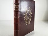 an old book with a brown cover sitting on top of a white table