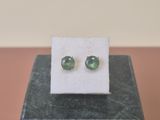 une paire de boucles d'oreilles en tourmaline verte posées sur un bloc de marbre
