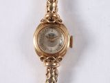 a gold watch with a chain around it on a white surface