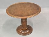 a small wooden table with a round top on a gray surface