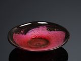 a glass bowl with a pink substance in it on a black surface