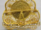 une image représentant une broche en or surmontée d'une horloge