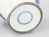 blue and white vase with a silver rim on a white surface