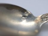 a silver spoon with a diamond on it sitting on a table