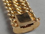 a close up of a gold chain bracelet with a square clasp