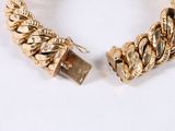 two gold bracelets on a white surface with a white background