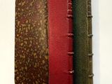 un vieux livre à la couverture rouge et verte posé sur un mur blanc