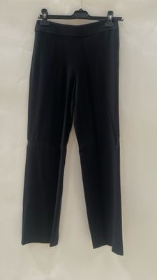 a black pants hanging on a hanger on a wall