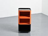 an orange and black cabinet in a white room with a gray floor