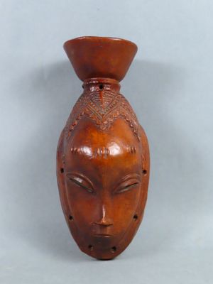 un vase marron orné d'un visage, posé sur une table