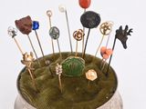 a small metal pin holder with pins and pins in it