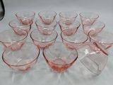 twelve pink depression glasses on a white tablecloth