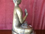 statue of a seated buddha on a wooden table with a pink background