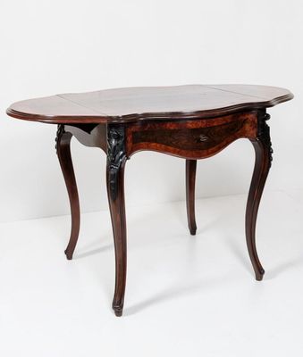 une table à manger ovale avec un plateau en marbre et des pieds sculptés