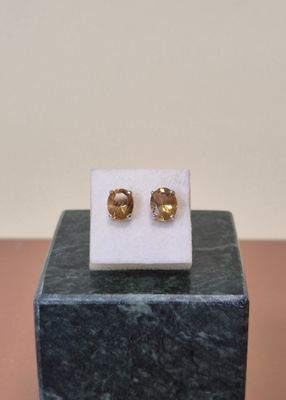 un gros plan sur une paire de boucles d'oreilles en or posées sur un bloc de marbre