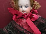 a doll that is sitting on the floor wearing a red dress