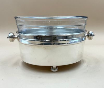 un plateau en argent muni d'un couvercle en verre, posé sur une table