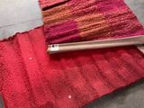 un tapis rouge posé par terre, à côté d'un rouleau de moquette