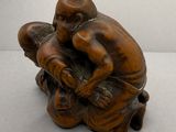 une petite statue représentant un homme et un enfant assis par terre