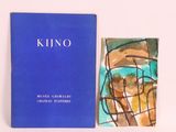 a blue book sitting next to a painting on a white surface