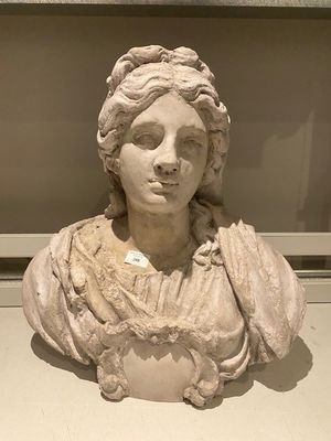marble bust of a woman with curly hair in a glass case