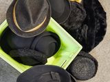 Plusieurs bonnets et gants sont posés dans une boîte verte posée par terre.