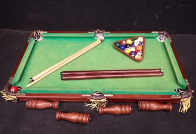 une table de billard sur laquelle se trouvent un triangle et des queues