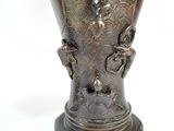 a bronze vase with a bird on it on a pedestal