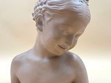 a small statue of a young boy with a flower in his hair