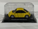a yellow toy car in a clear case on a white surface