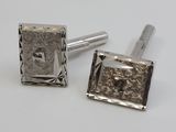 two silver cufflinks with a square design on them