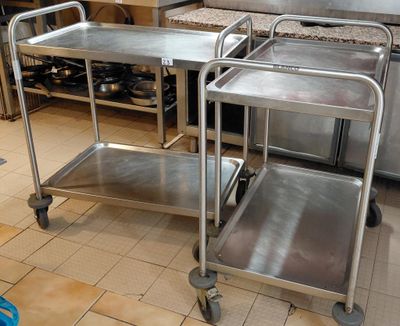 two stainless steel trolleys in a kitchen with a stove in the background