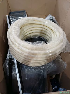 a cardboard box filled with a large coil of white hose