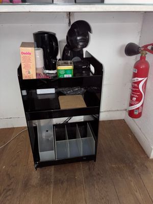 une étagère noire sur laquelle sont posés divers objets et un extincteur