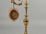 gold plated clock on a stand with a red and gold decoration