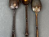 three silver spoons and two silver spoons sitting on a table