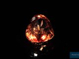 a close up of an orange diamond on a black surface