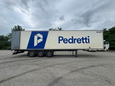 a white semi truck with a blue and white logo parked in a parking lot