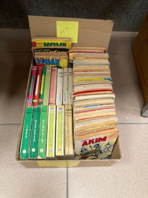 une boîte remplie de livres posée par terre, à côté d'une autre boîte de livres